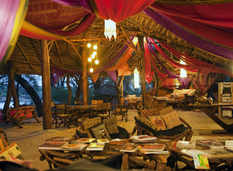 Elephant Watch Camp, exquisite indoor lounge area with multicolored canopy descending from the vaulted ceilings above beautiful furniture, Kenya
