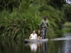 Jacana camp, poled canoe for travelers with guide, Okavango Delta, vibrant green flora surrounding deep colored waters, Africa, Botswana