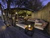 Khalahari Plains Camp, outdoor lounge area with overhanging tree, raised wooden platfom with comfotable couches, intimate lighting, Botswana, Africa