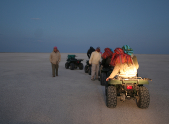 A group of safari tourists takes a night ATV ride through the Kalahari Desert wearing bandanas to prevent sand from getting in their faces