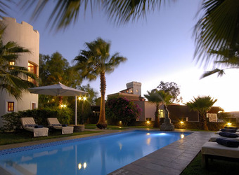 Picturesque light blue opal colored pool surrounded by grey tiles and lounge chairs for relaxing by the hotel in Windhoek, Namibia