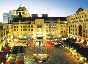 Gorgeously constructed building architecturally along with a nice plazza and a variety of cars and people in downtown Johannesburg, South Africa