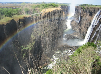 The multitudes of water cascade over Victoria Falls as a rainbow paints a stunning vista of the Zambezi Gorge in Zimbabwe
