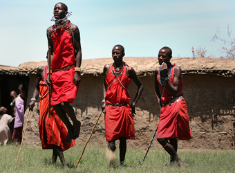 Local villagers and native peoples perform a traditional dance wearing traditional garb in Maasai Mara National Reserve, Kenya