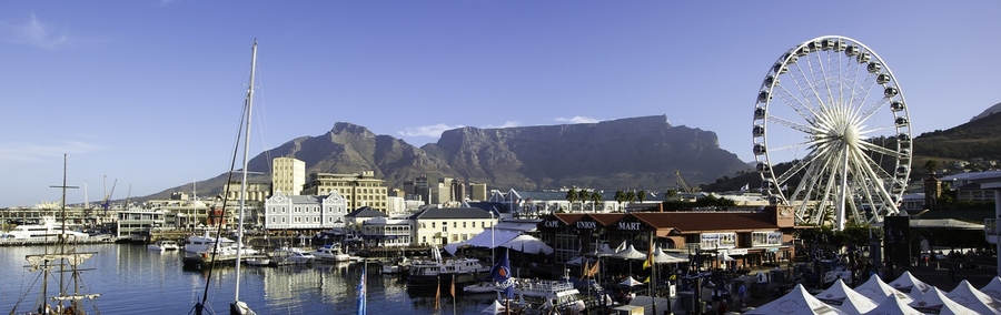 Victoria & Alfred Waterfront, Cape Town, South Africa, view of waterfront town with sweeping mountains in the background, ferris wheel, old sailboats