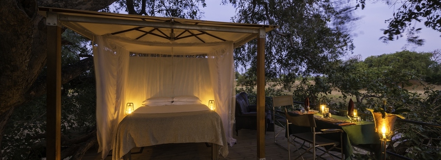 New luxurious sleepout at Ruckomechi safari camp, beautifully lantern lit outdoor bed safely enclosed within the camp, secluded private dining table