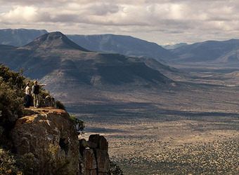 Massive rich mountains seemingly springing up straight out of the deeply colored earth with guests on cliff edge in the eastern cape, South Africa